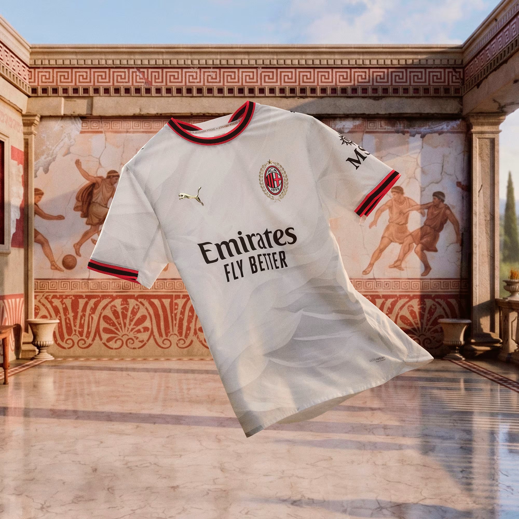 A white AC Milan soccer jersey with red and navy trim, featuring the Puma logo, AC Milan crest, and Emirates Fly Better sponsor text, shown floating in front of a classical fresco background.