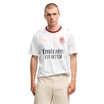 A male model wearing a white Puma AC Milan soccer jersey with the Emirates Fly Better sponsor logo, paired with beige trousers, against a plain white background.