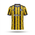 A yellow and black patterned soccer jersey with a V-neck, featuring a 'KEN team' sponsor logo on the chest, a circular club crest, and a stylized 'AL' logo on the right chest. The jersey is displayed on a clean white background with a soft drop shadow.