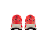 A pair of Nike running shoes shown from the back, featuring a bright coral-red mesh upper, a beige midsole, and black outsole details.