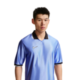 A man wearing a light blue Nike soccer jersey with a black collar and black sleeve trim, photographed against a solid white background.