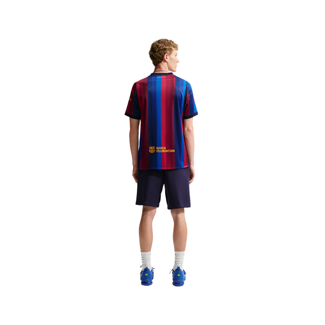 A model shown from the back wearing a Barcelona football jersey with red and blue vertical stripes, navy shorts, white socks, and blue sneakers on a solid white background.