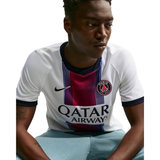 A man wearing a Paris Saint-Germain Nike soccer jersey with a white base, navy and red vertical stripes, and a 'Qatar Airways' sponsor logo, paired with light blue shorts against a white background.