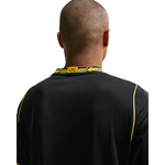 Back view of a man wearing a black athletic jersey with yellow piping and a yellow neck label that reads 'CPO'.