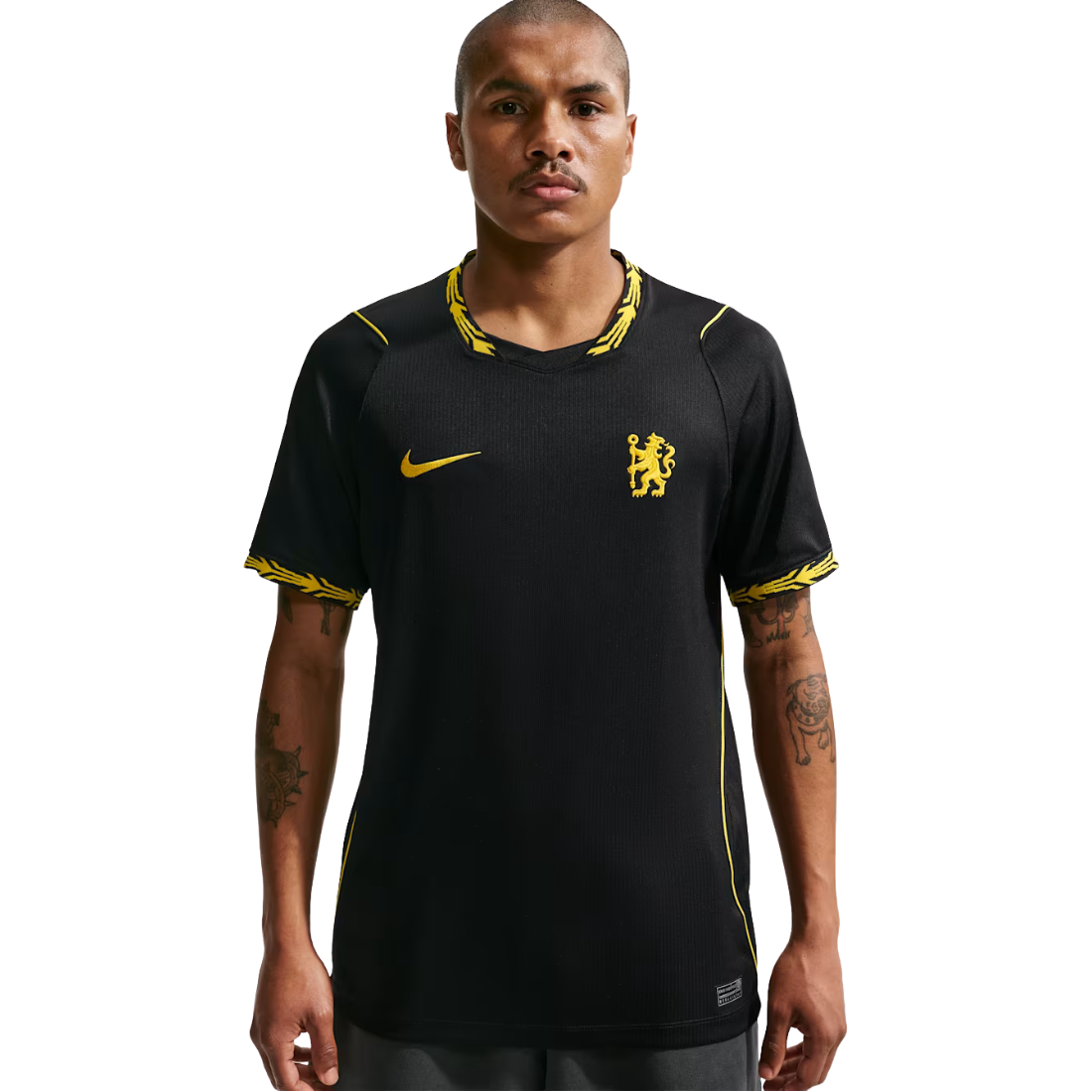 A man modeling a black Chelsea FC Nike soccer jersey with yellow accents, including the Nike swoosh and club crest, against a plain white background.